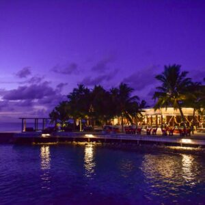 A breathtaking view of a tropical resort at twilight, surrounded by palm trees and reflecting on the ocean.