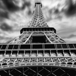 A striking black and white perspective of the Eiffel Tower under dramatic clouds in Paris.