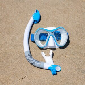 Blue and white snorkeling mask and snorkel on a sandy beach, ready for adventure.
